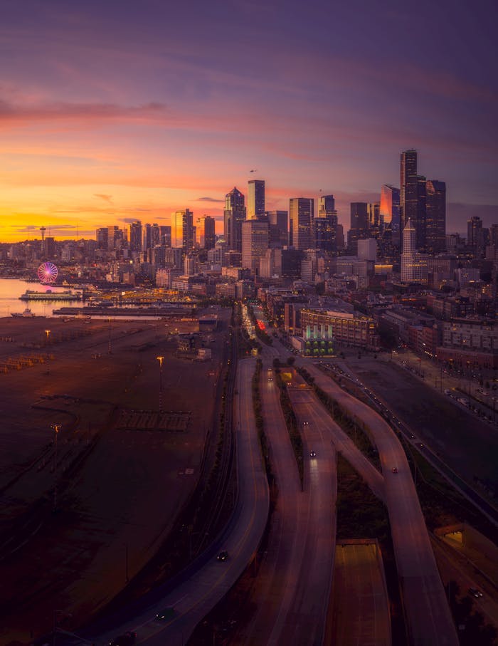 gallery-02 Aerial view of Seattle skyline at sunset featuring highways and vibrant colors.
